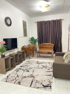 ein Wohnzimmer mit einem Sofa und einem TV in der Unterkunft ELLY HOMESTAY in Kuala Terengganu