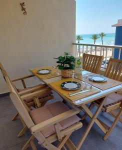 a wooden table with chairs and a table with a view of the beach at App.Pradomar Peñiscola in Peniscola