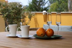 einem Holztisch mit zwei Tassen und Orangen darauf in der Unterkunft Chalet en Comillas in Comillas