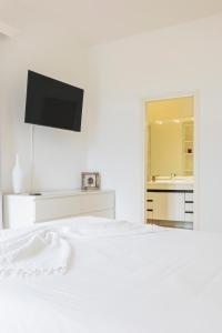 a white bedroom with a bed and a tv on the wall at Villa Magnolia - High standing floor in Locarno
