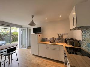 a kitchen with white cabinets and a table and a counter top at La terrasse des Thermes, Jura in Lons-le-Saunier +13 photos