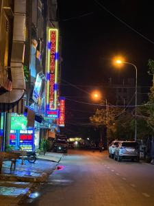 una calle de la ciudad por la noche con carteles de neón en Nhan Tay Hostel, en Can Tho