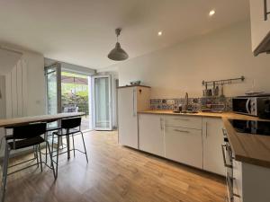 a kitchen with white cabinets and a table and chairs at La terrasse des Thermes, Jura in Lons-le-Saunier
