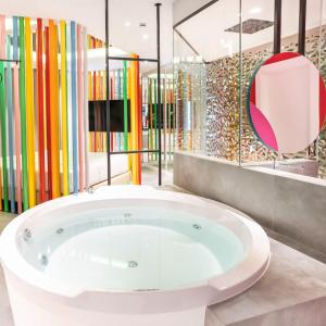 a large tub in a room with colorful glass partitions at Hotel Avenue - Lovely hotel in Madrid