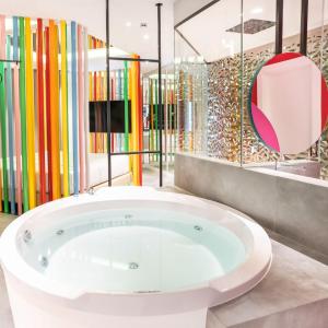 a large tub in a room with colorful glass partitions at Hotel Avenue - adults only in Madrid +43 photos