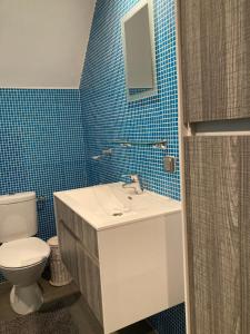 y baño con lavabo, aseo y azulejos azules. en Gastroatelier en Gooik