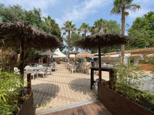 patio ze stołami, krzesłami i parasolami w obiekcie Camping de l'Arnel w mieście Villeneuve-lès-Maguelone