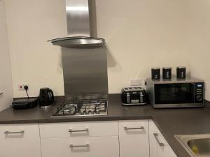 a kitchen with a stove top oven next to a microwave at MODERN 4 BEDROOM HOUSE WITH GARDEN & PARKING in Swanscombe
