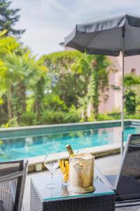 Villa Magnolia - High standing floor في لوكارنو: طاولة مع الشراب وكأس النبيذ ومظلة