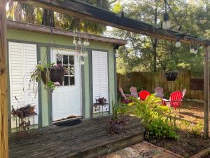 - une terrasse couverte avec une porte blanche et des chaises rouges dans l'établissement 3BR/3BA Charming Key West Style Home in Downtown Saint Augustine, à Saint Augustine