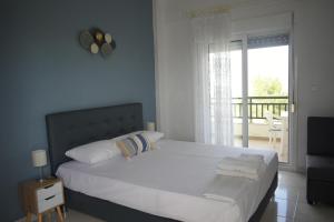 a bedroom with a large white bed with a balcony at Elegant Maisonettes Elena in Nea Potidaea