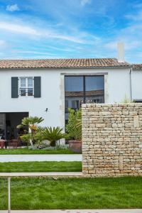 uma casa branca com uma parede de pedra em Maisons 322 - La Flamboyante em Le Bois-Plage-en-Ré