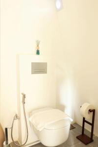 a white bathroom with a toilet and a roll of toilet paper at Asmara Lifestyle Hotel in Cebu City