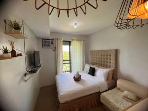 una camera da letto con un letto, una TV e un divano di CozyVilla at Pine Suites Tagaytay 2BR or Studio with FREE PARKING 2br in Basement parking and studio in offsite parking a Tagaytay
