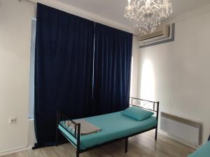 a bed in a room with blue curtains and a chandelier at Mejdan II in Mostar