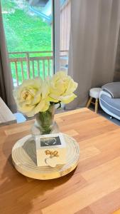 蒂涅的住宿－Le Petit Chalet Addicted to Paradise，一张带黄花的花瓶,放在桌子上,放一张卡片