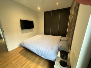 een slaapkamer met een bed en een flatscreen-tv bij BadHoophuizen 6-per Bungalow Veluwemeer Trampoline in Hulshorst