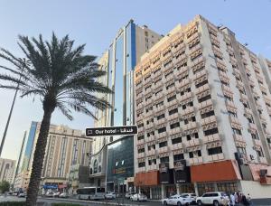 a palm tree and a street sign in front of a building at فندق كنان العزيزية Kinan Al Azizia Hotel Makkah in Mecca