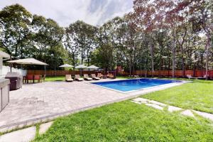 a swimming pool in a yard with chairs and umbrellas at Brand new house with an all year round hot tub. in Westhampton Beach