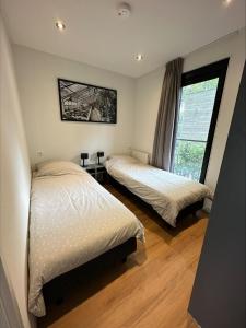 een slaapkamer met 2 bedden en een raam bij BadHoophuizen 6-per Bungalow Veluwemeer Trampoline in Hulshorst