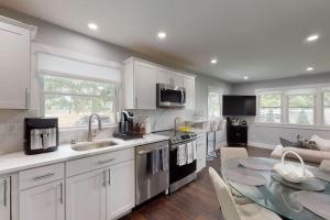 a kitchen with white cabinets and a table with a dining room at Brand new house with an all year round hot tub. in Westhampton Beach