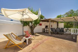 een patio met 2 stoelen en een parasol bij Casa Solar in Guia
