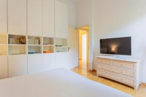 a white bedroom with a bed and a tv on a dresser at Villa Magnolia - Boutique Superior Rooms in Locarno
