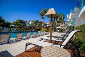 a row of chairs sitting next to a swimming pool at Varandas do Atlântico 101A - Excelente apartamento em condomínio de luxo a beira mar - Piscina climatizada - Academia - (Consultar serviços de roupas de cama e banho) in Bombinhas