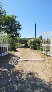 une porte sur un chemin de terre avec des arbres et des buissons dans l'établissement Cozy Corfu Bungalow 5 minutes to Aqualand, à Corfou