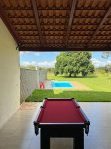 einen roten Billardtisch im Hinterhof mit Pool in der Unterkunft Sitio chácara rancho bonanza in Uberlândia