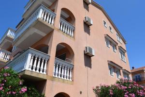 un edificio de ladrillo con balcón y flores rosas en Apartments Lavanda, en Crikvenica