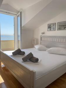a bedroom with a large white bed with a view of the ocean at Villa Viden Apartments in Tučepi
