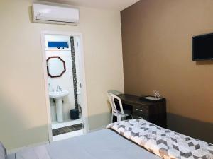 a bedroom with a bed and a sink and a desk at Conforto entre a UFSM e o centro in Santa Maria