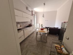 a kitchen with white cabinets and a table and a refrigerator at Costa del Sole in Salerno