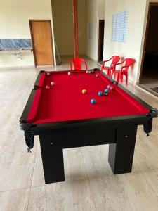a red pool table in a room with red chairs at Sitio chácara rancho bonanza in Uberlândia