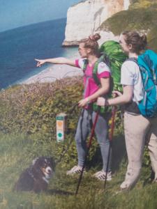 two women and a dog on a hill with their backpacks at L'Escapade in Gonneville-la-Mallet