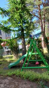 eine grüne Schaukel in einem Garten mit Bäumen in der Unterkunft Villa Azalia in Jastrzębia Góra