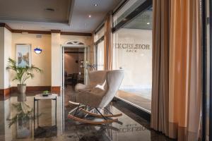 a salon with a chair in front of a window at Hotel Excelsior in Lido di Jesolo