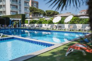 a large swimming pool with chairs and umbrellas at Hotel Excelsior in Lido di Jesolo