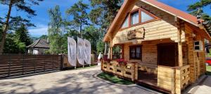 Cabaña de madera pequeña con valla y árboles en Domek z Bala Pod Żaglami en Pobierowo