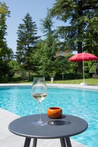 una copa de vino sentada en una mesa junto a una piscina en Domaine des Granges Longes en Les Marches