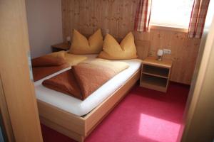 a small bedroom with a bed with pillows and a window at Haus Lutea in Gaschurn