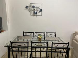 a dining room table with four chairs and a clock on the wall at La Posada Manabita in Portoviejo