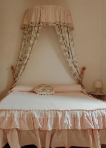 Cama con dosel con colcha y cortinas blancas en La Dolce Vita, en Pitigliano