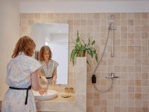 a woman standing in front of a sink in a bathroom at La Boule d'Or - Auberge créative in Clamecy