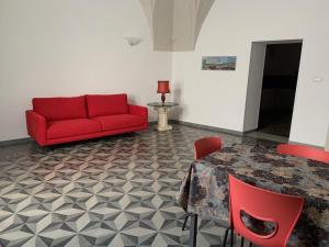 ein Wohnzimmer mit einem roten Sofa und einem Tisch in der Unterkunft B&B Lecce26 in San Pietro Vernotico