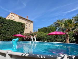 uma piscina com dois guarda-sóis e uma piscina em L'Oustaloise em Faugères