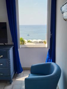 a blue chair and a window with a view of the ocean at varazze suite endless sea in Varazze
