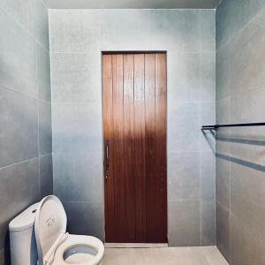 a bathroom with a toilet and a wooden door at Mega Canggu Guest House in Canggu +10 photos