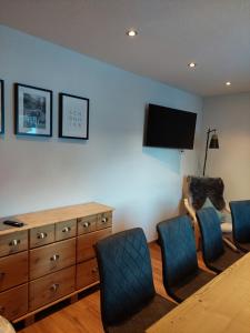 a living room with a wooden dresser and blue chairs at Ferienwohnung CASADA im Hotel Casada in Galtür